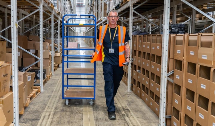 man walking through a warehouse with a trolley