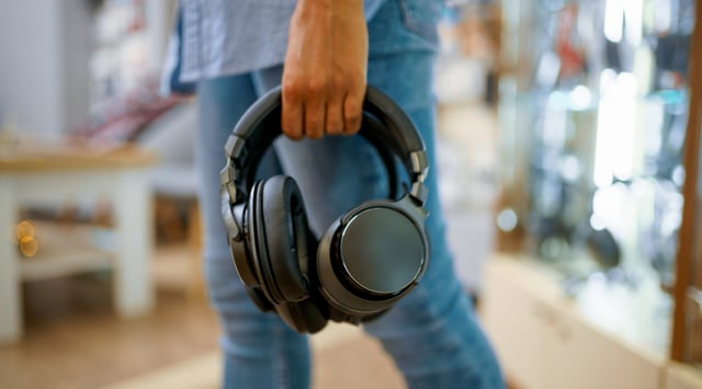 Headphones being held by a person in a studio setting
